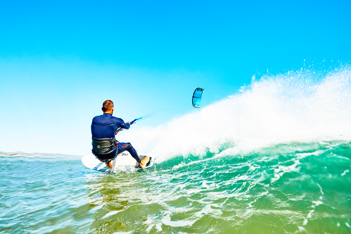 Guy kite surfing a wave in Essaouira beach in a sunny day.